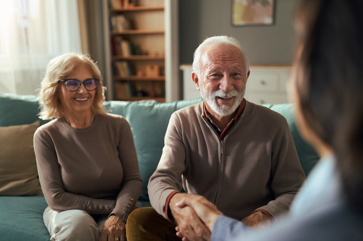 Happy senior couple reached agreement with their financial advisor at home